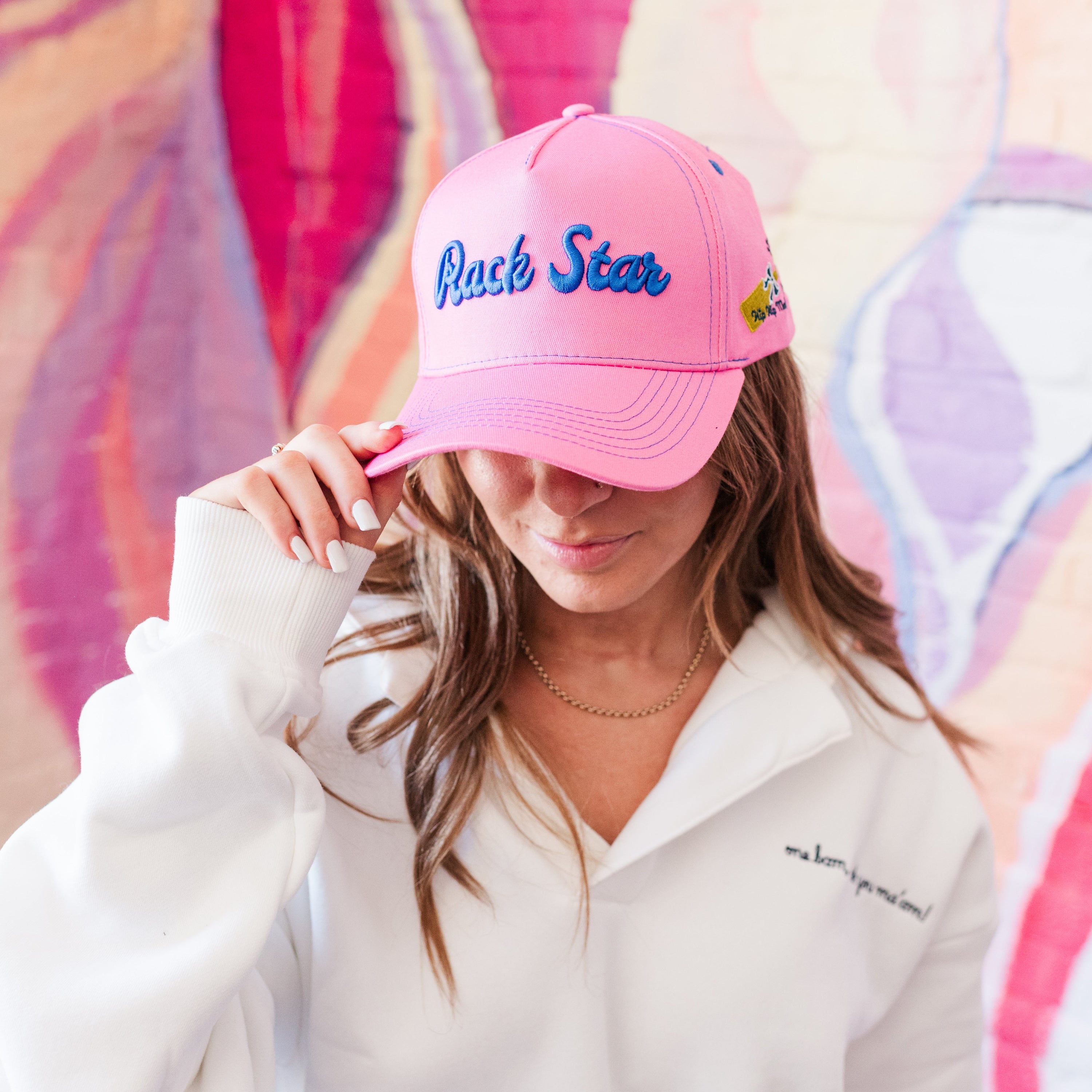 A person wearing a pink baseball hat with &