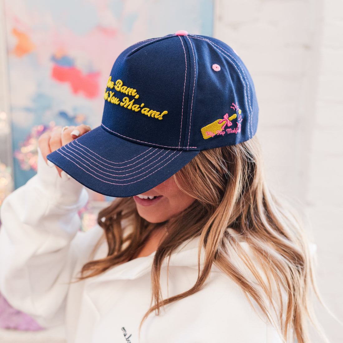 Person wearing a navy blue cap with colorful text and designs, against a light background.