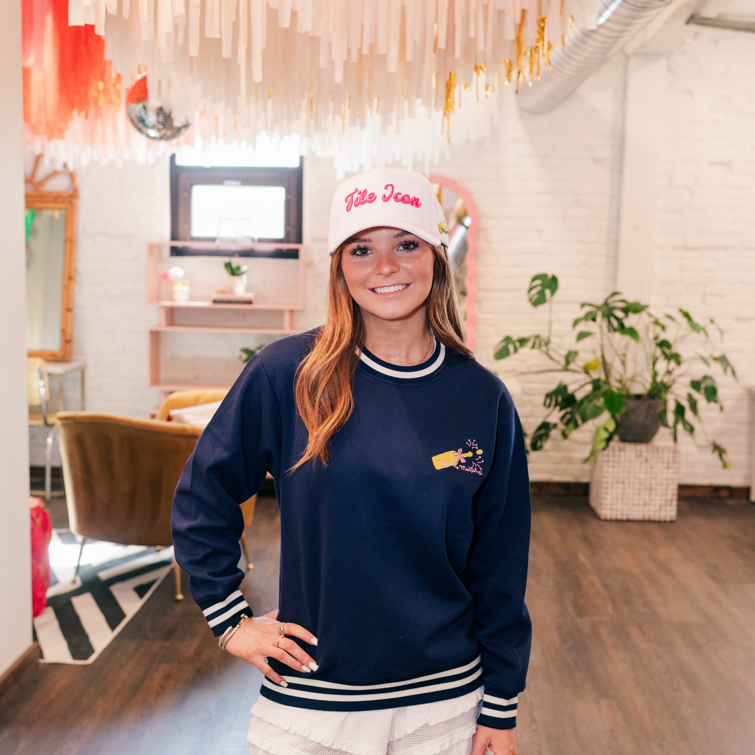 Woman wearing a navy sweatshirt and white shorts in an indoor setting with decor elements.